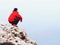 Thinking man sit on rock. Man on view point of exposed peak watching to misty far distance.