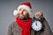 Thinking mature man wearing Santa hat holding big alarm clock looking up