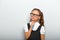 Thinking serious skeptical pupil girl in fashion eyeglasses with in school uniform with pencile inder the face