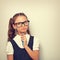 Thinking serious skeptical pupil girl in fashion eyeglasses with in school uniform with pencile inder the face