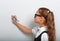 Thinking smiling pupil kid girl in eyeglasses drawing pencil on the blue wall