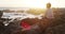 Thinking, young kid and sitting on beach rock by the sea watching a wave at sunset. Child, idea and contemplation in