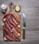 Thinly sliced lamb with garlic on a cutting board with a knife for meat, butter and salt border ,text area on wooden rustic b