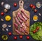 Thinly sliced lamb with garlic on a cutting board with a knife for meat, butter and salt, lettuce on wooden rustic background top