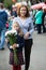 Third-grade girl with bouquet of chamomiles standing in schoolyard with mother, portrait