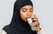 Thirsty black muslim woman in hijab drinking mineral water from glass