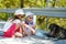 Thirsty black stray dog drinking water from the plastic bottle on hot summer day. Two kids giving cool water to thirsty dog