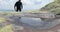 A thirsty and fit tourist runs up and drinks from a small puddle in harsh mountain