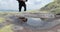 A thirsty and fit tourist runs up and drinks from a small puddle in harsh mountain