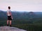 Thirsty hiker in black pants with bottle of water. Sweaty tired tourist on the peak of sandstone rocky park Saxony Switzerland wat