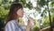 Thirsty woman drinks cold clean water and smiles on background trees in park on nature