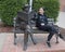 Thirteen year-old girl posing humorously with bronze of Will Rogers on a bench, Claremore, Oklahoma