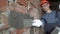 A thirty-year-old worker with plastering tools repairs a house. A plasterer repairs interior walls with a trowel and