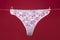 Thong bikini panties, white lace underwear lingerie on rope isolated on red background.