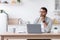 Thoughtful adult caucasian male blogger in glasses working at computer on kitchen interior