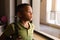 Thoughtful african american elementary schoolboy standing by window while standing in classroom