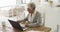 Thoughtful african american senior woman taking notes and using laptop at home