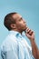 Thoughtful Afro-American man is looking thoughtfully against blue background