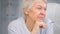 Thoughtful aged lady with sad eyes wrinkly face alooks aside holding glasses in hand