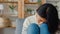 Thoughtful Asia lady sit embracing knees at sofa in living room at house look outside with feel lonely, Sad depressed teenager