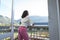 Thoughtful biracial young woman looking away and leaning on railing in balcony seen through doorway