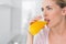 Thoughtful blond woman drinking orange juice