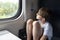 Thoughtful boy sits in compartment carriage and looks in window. Travel by railway
