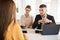 Thoughtful business man with laptop and business woman with pencil and folder in hands talking with applicant about work