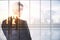 Thoughtful business man standing in abstract city interior with view, sunlight and mock up place. Brainstorm, teamwork, future and