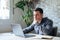 Thoughtful businessman touching chin, pondering ideas or strategy, sitting at wooden work desk with laptop, freelancer working on