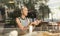 Thoughtful caucasian woman holding mobile phone while looking through the coffee shop window during coffee break.