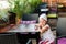 Thoughtful charming little girl with a white turban on her head at a table in a cafe