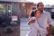 Thoughtful Couple Standing Outdoors In Front Of House With For Sale Sign In Garden