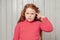 Thoughtful cute redhead preteen girl deep thinking, looking at camera with pondering face, making choice