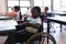 Thoughtful disable schoolboy looking away at desk in classroom