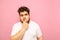 Thoughtful fat young man with curly hair and beard stands on a pink background and looks thoughtfully aside for a blank space. Guy