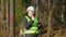 Thoughtful forest engineer with tablet PC near tree