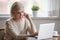 Thoughtful frustrated woman sitting at table near laptop