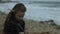 Thoughtful girl looks at the sea in the winter in windy weather