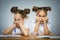 Thoughtful girls sitting at desk on gray background. school concept