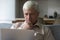 Thoughtful grey-haired mature man learning laptop app or software