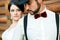 Thoughtful groom in hat with beard, mustache, bow tie and suspenders. Bride wearing white wedding dress. Gangster style.