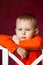 Thoughtful little blond boy sitting on a white kitchen chair as he stares at the camera. Cute little boy is bored during