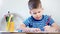 Thoughtful little cute boy enjoying inspiration drawing creative picture using red pencil