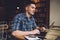 Thoughtful male student in smart casual shirt sitting at table desktop