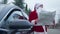 Thoughtful man in red Santa costume standing at car with map looking for direction. Portrait of embarrassed Caucasian