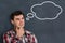 Thoughtful man with thought bubble on blackboard