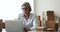Thoughtful mature entrepreneur woman working at laptop in e-commerce storage