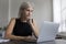 Thoughtful mature freelancer woman working at laptop at home