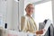 Thoughtful mature lady tailor holds papers in light sewing workshop